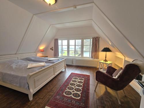 a bedroom with a bed and a chair and a window at Ilskes Hus in Oevenum