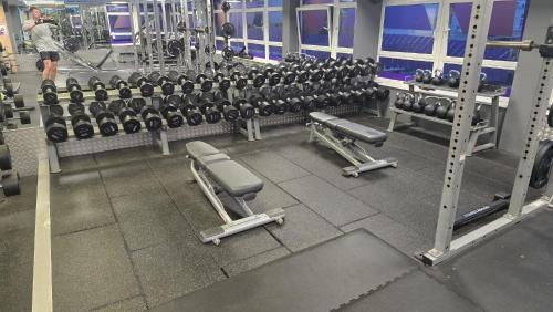 a gym with rows of dumbbell machines and a man walking at The Castle Suite 24h Gym Free Parking in Kenilworth