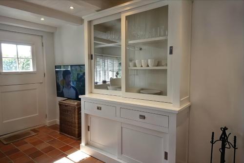 a kitchen with white cabinets and a window and a television at Pastoratshof - Haus 6 in Wrixum