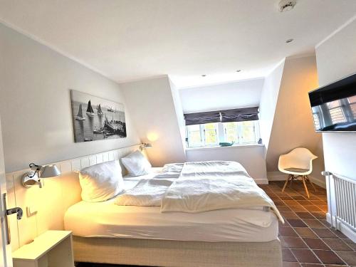 a bedroom with a large white bed with two windows at Pastoratshof - Haus 6 in Wrixum