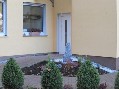 a garden in front of a house with two trees at Hotel Goldbächel in Wachenheim an der Weinstraße