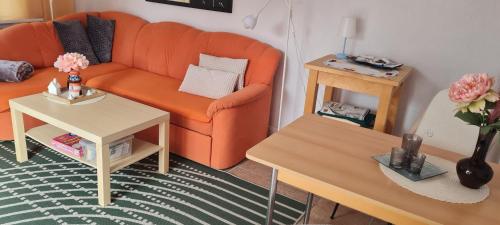 a living room with an orange couch and a table at Ferienwohnung im Leuchtturmort Bastorf in Bastorf