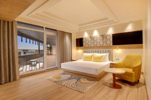 a bedroom with a bed and a chair and a window at Lemon Tree Hotel, Bhubaneswar in Bhubaneshwar
