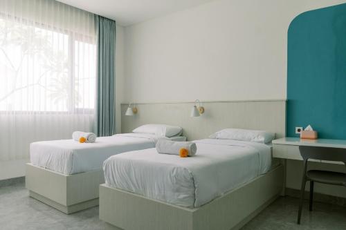 a room with two beds and a desk and a window at Domu Alba Vita in Denpasar
