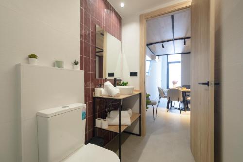 a bathroom with a toilet and a dining room at Apartamentos Nevada Metro con PARKING GRATIS in Maracena