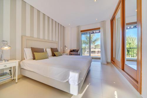 a bedroom with a large white bed and a balcony at Villa Magnolia The Crest 3 quartos e piscina in Almancil