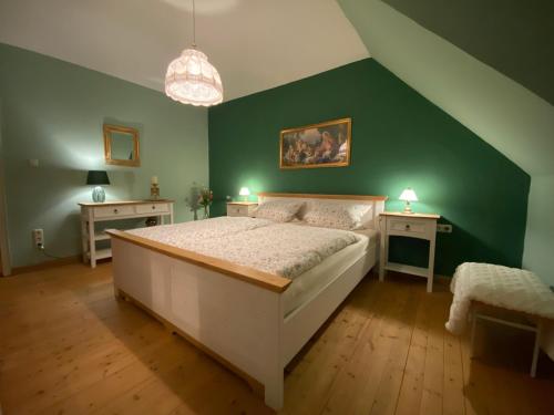 a bedroom with a white bed and green walls at Ferienhaus Soonwald in Schwarzerden