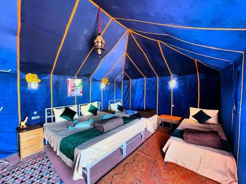 a bedroom with two beds in a blue tent at Luxury Suerte Camp in Merzouga