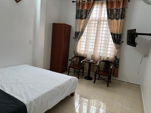 a bedroom with a bed and chairs and a window at Nhà nghỉ thảo chung in Kỳ Lừa