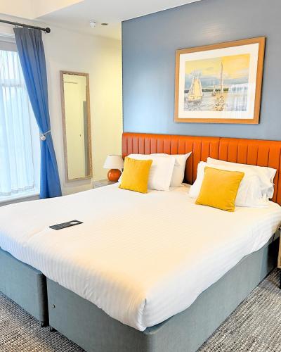 a bedroom with a large bed with yellow pillows at Haslar Rooms in Gosport