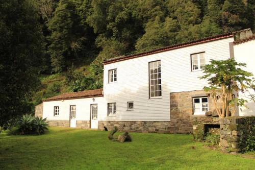a house with two dogs sitting in the grass in front of it at Aldeia do Sanguinho in Faial da Terra