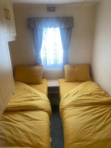 two beds in a small room with a window at KC Caravans in Ingoldmells