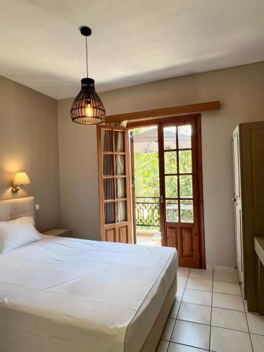 a bedroom with a white bed and a glass door at Fenareti Apartments in Skala Eresou