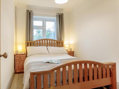 a bedroom with a wooden bed with a window at 2 Bed in Swansea oc-77978 in Penclawdd