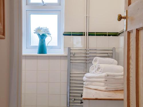 a bathroom with a stack of towels and a window at 2 Bed in Swansea oc-77978 in Penclawdd