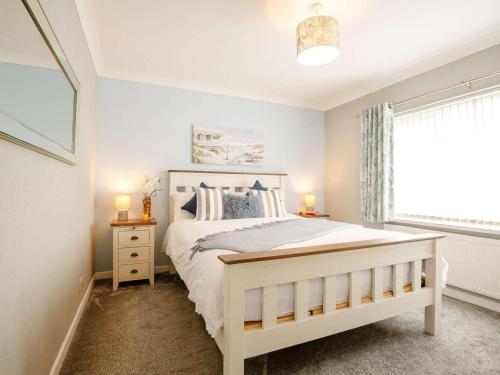 a bedroom with a white bed and a window at 2 Bed in Moelfre oc-75013 in Moelfre