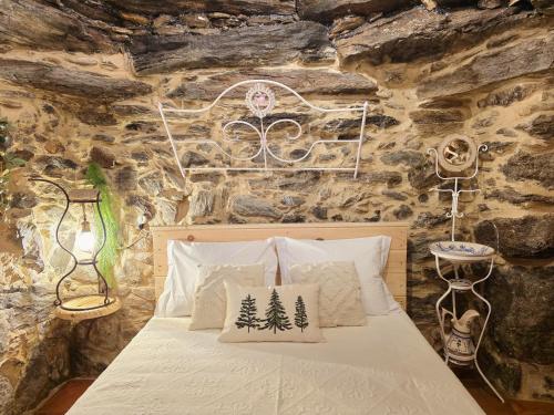 a bedroom with a bed in a stone wall at Cardenha das Formiguinhas in Monção