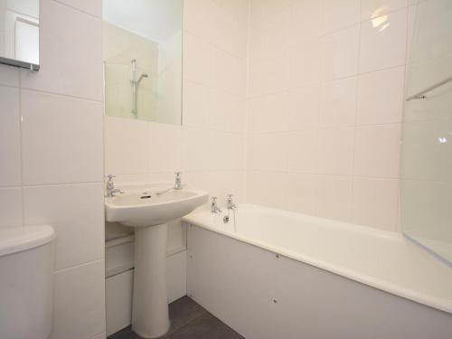 a white bathroom with a sink and a bath tub at 2 Bed in Saundersfoot oc-74356 in Saundersfoot