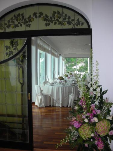a dining room with white tables and flowers at Tramonto d'Oro in Praiano