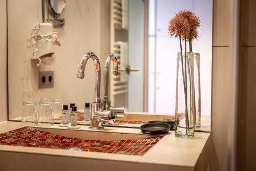 a bathroom counter with a sink with a vase of flowers at Hotel Salinensee in Bad Dürrheim