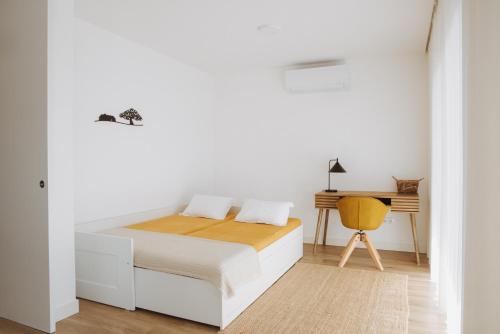 a white bedroom with a bed and a desk at Casa D'Almo in Almograve