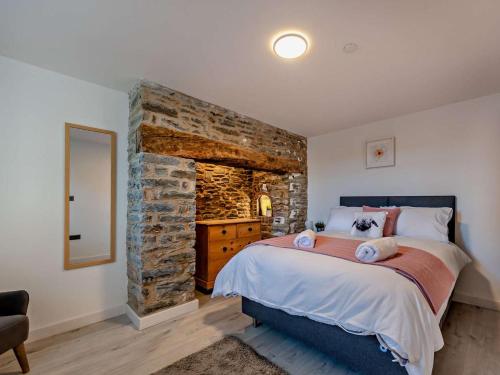 a bedroom with a large bed and a stone wall at 4 Bed in Llandovery oc-90307 in Myddfai