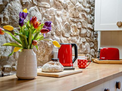 a vase filled with flowers sitting on a kitchen counter at 1 Bed in Swansea oc-77981 in Penclawdd