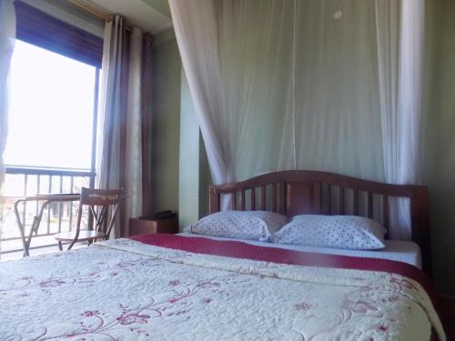 a bedroom with a bed and a window with a view at Hotel Shine Sunet in Mbarara