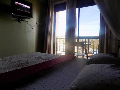 a bedroom with a bed and a tv and a window at Hotel Shine Sunet in Mbarara