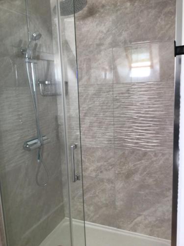 a shower stall with a glass door with a shower at Pinabre Rose Cottage in Plouguenast Langast