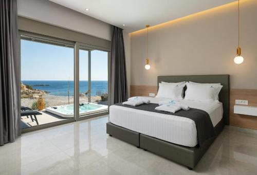a bedroom with a bed and a view of the ocean at Aquamarine Luxury Suites - Stegna - Beachfront, Jacuzzi , Smart Home, Great View in Archangelos