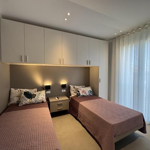 two beds in a bedroom with white cabinets at A&G green flat il mare e Venezia in Cavallino-Treporti