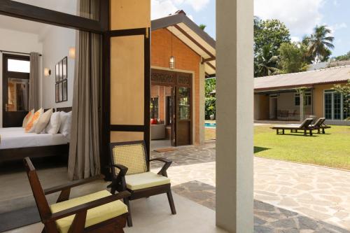 a room with a bed and a chair on a patio at Divulgaha Gedara Boutique Hotel in Anuradhapura