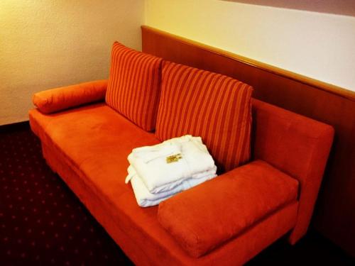 an orange couch with a white purse on it at Hotel Goldbächel in Wachenheim an der Weinstraße
