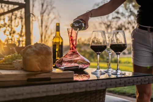 a person pouring wine into wine glasses on a table at Norm's Vineyard Retreat in Lyndoch