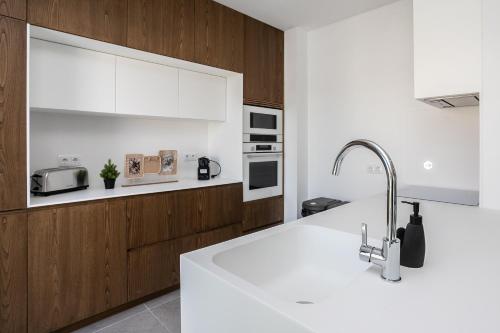 a kitchen with white counter tops and wooden cabinets at Serena By Marenssa in Moncarapacho