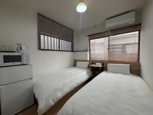 a small room with two beds and a microwave at KIX Nest in Izumi-Sano