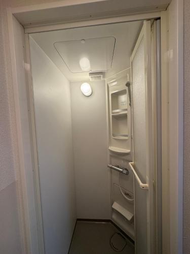 a small bathroom with an open door and a refrigerator at KIX Nest in Izumi-Sano