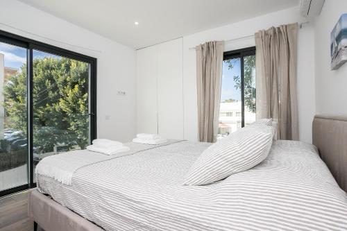 a white bedroom with a bed and a large window at Serena By Marenssa in Moncarapacho