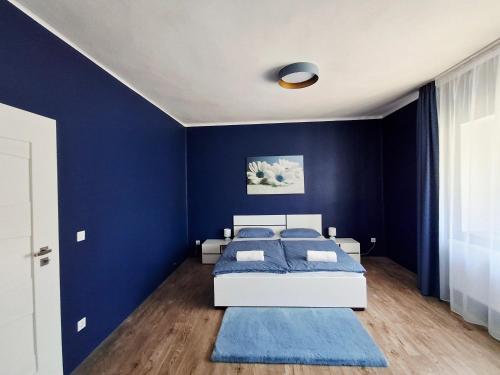 a bedroom with blue walls and a white bed at SZEDERMÁLNA Vendégház in Sárospatak