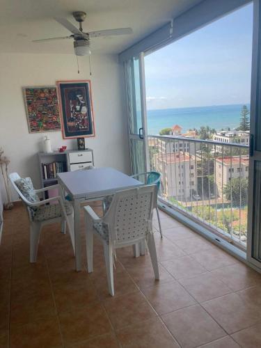 a dining room with a table and chairs and a balcony at Sea & Mountain Views Benicassim in Benicàssim