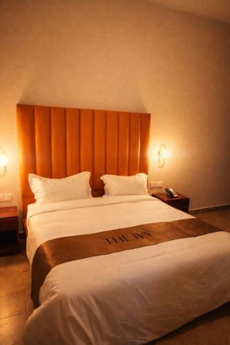 a hotel room with a large bed with a wooden headboard at The Ivy Hotel in Lusaka