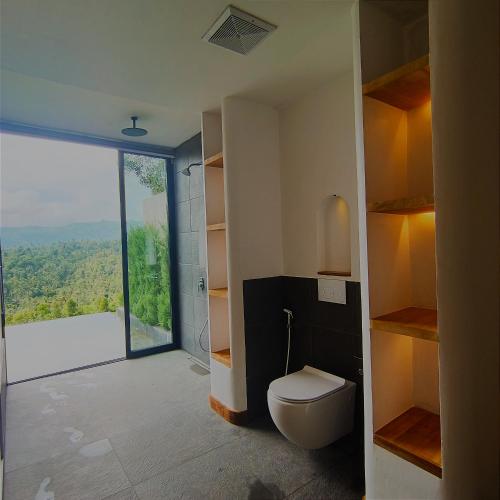 a bathroom with a toilet and a large window at Bali De Pardis Cottage in Munduk
