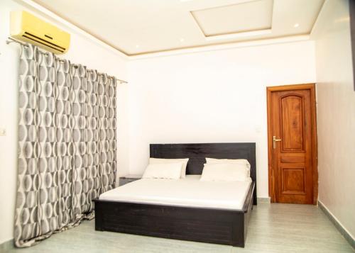 a bedroom with a bed and a wooden door at Résidences Amana in Porto-Novo