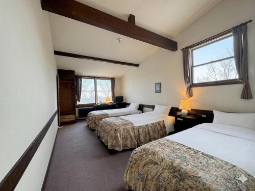 a room with three beds and a window at リゾートインブローニュ in Yanaike