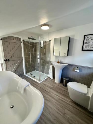 a bathroom with a tub and a shower and a sink at The Beach House in Mablethorpe