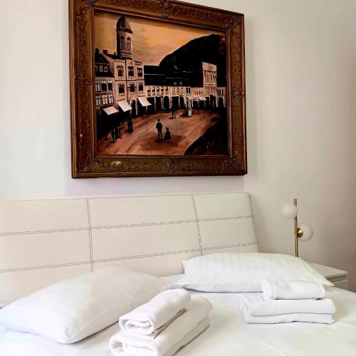a painting above a bed with two towels on it at Noemi Old Town in Braşov
