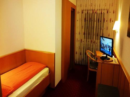 a small room with a bed and a desk with a computer at Hotel Goldbächel in Wachenheim an der Weinstraße