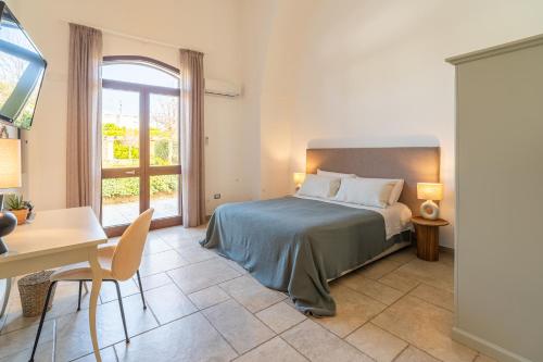 a bedroom with a bed and a desk and a window at Mediterranea Residence in Nardò