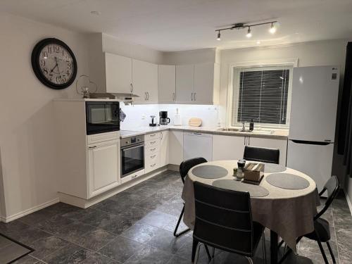 a kitchen with a table and a clock on the wall at Sokkelleilighet in Grindheim